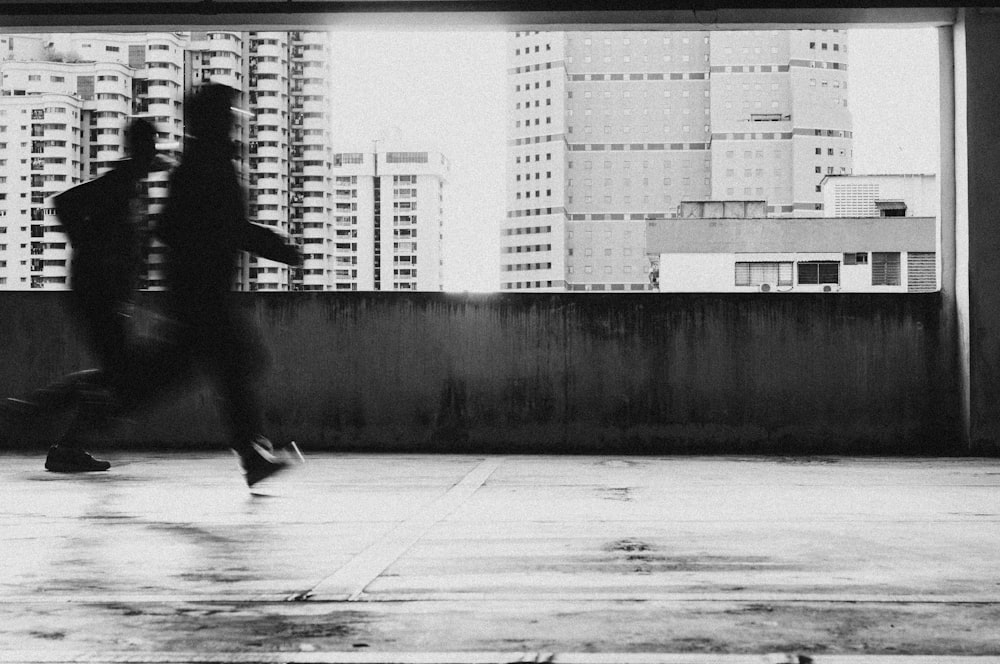 grayscale photo of man walking on sidewalk