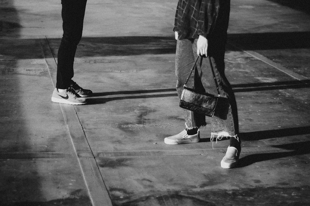 man in black pants and white sneakers walking on the street