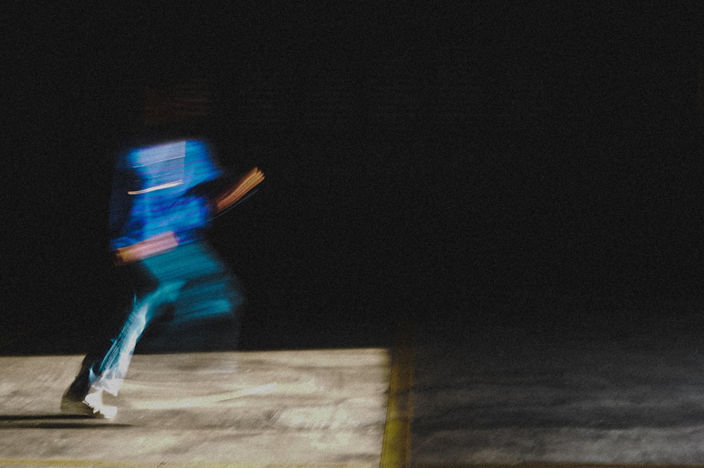 man in blue jacket and blue denim jeans walking on brown wooden plank during nighttime