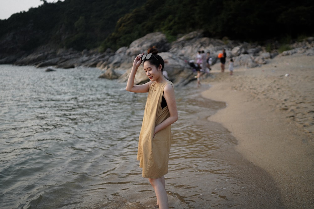 woman in yellow sleeveless dress standing on beach during daytime