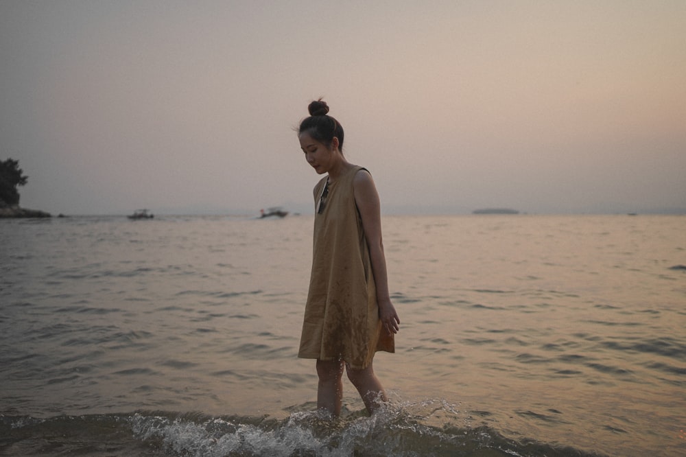 woman in brown dress standing on beach during daytime