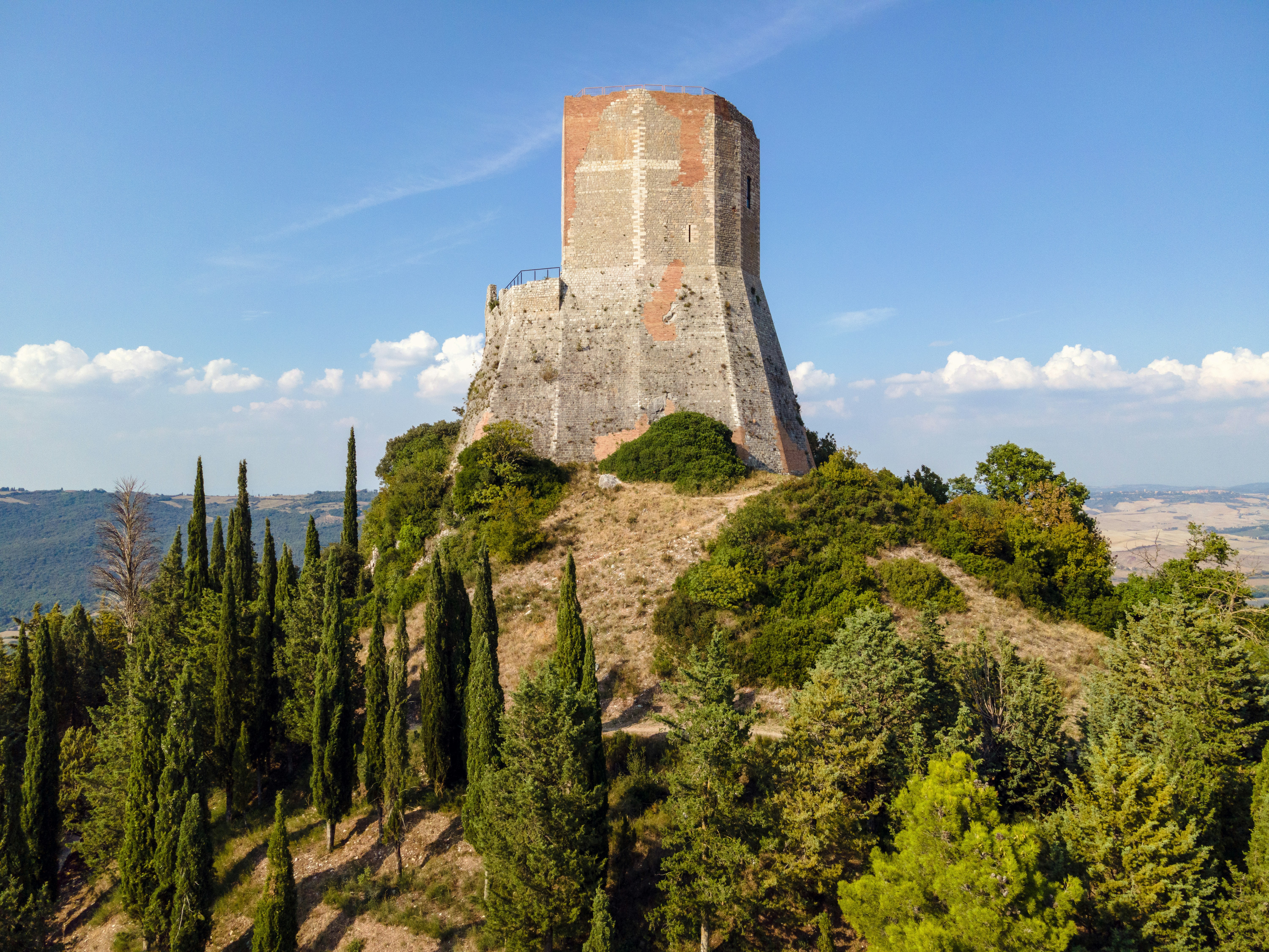 brown concrete building on top of hill, Fortress of Tentennano (12th century) in Tuscany where Saint Catherine of Siena received the gift of writing.