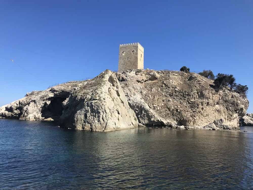 gray concrete building on gray rocky mountain near body of water during daytime