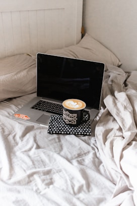 black and silver laptop computer on white bed