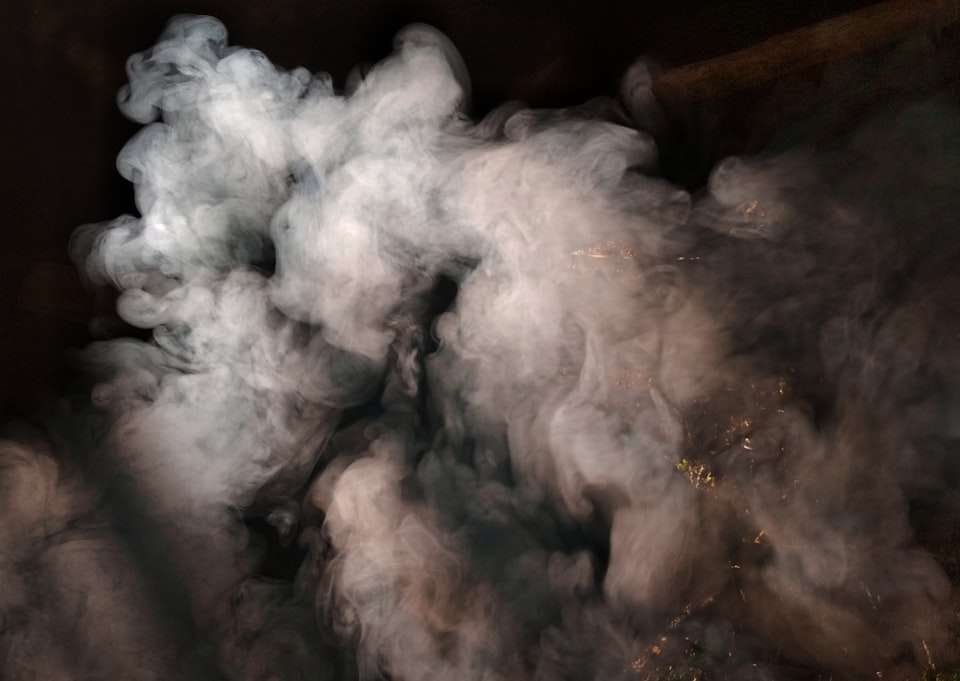 Pale grey smoke unfurling on a black background