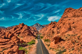 gray asphalt road between brown rocky mountains under blue sky during daytime