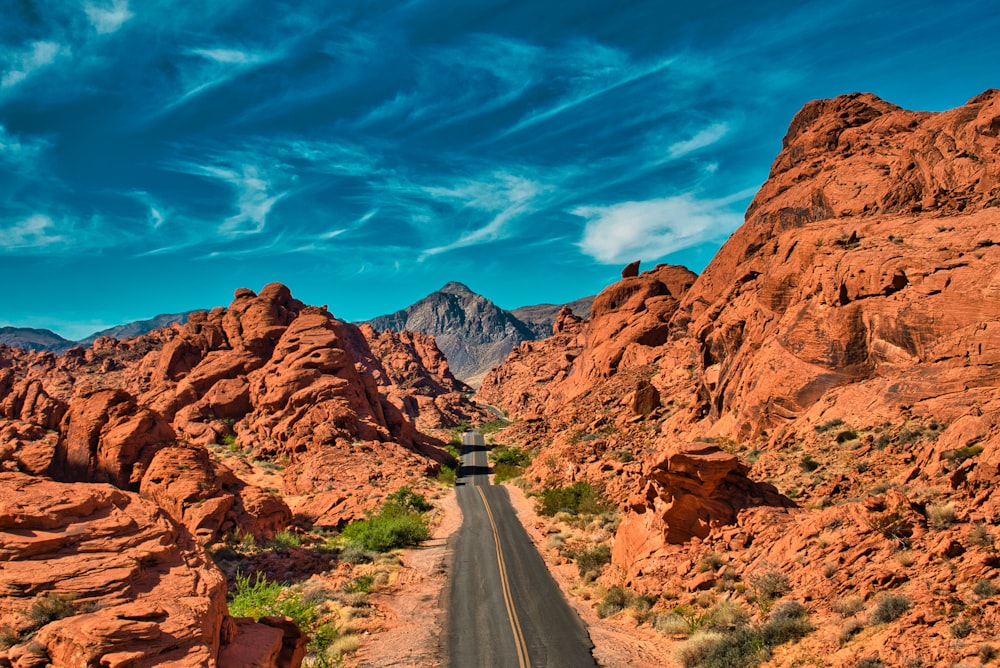 Carretera de asfalto gris entre montañas rocosas marrones bajo cielo azul durante el día