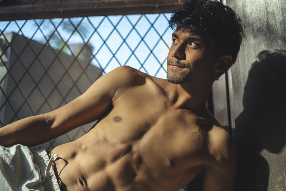 topless man standing near black metal fence