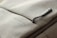 A close-up of a grey fabric bag with a zippered pocket. The word 'URBAN LIFESTYLE' is printed in white text on the fabric. The zipper pull has a small, rectangular, grey tag attached to it.