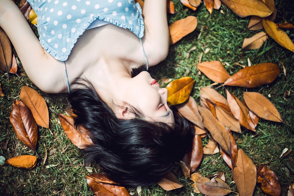 woman in white and blue polka dot shirt lying on green grass