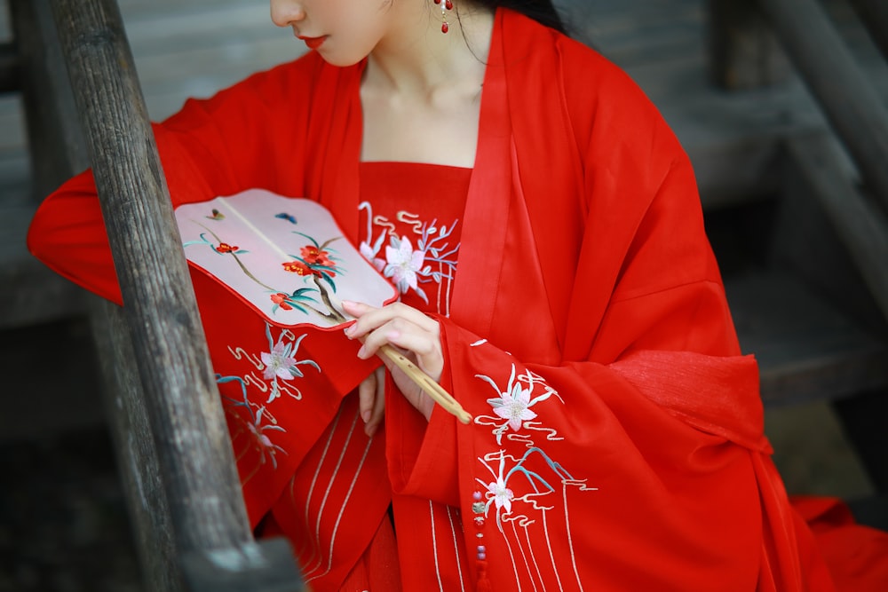 woman in red and white kimono holding white and red floral hand fan