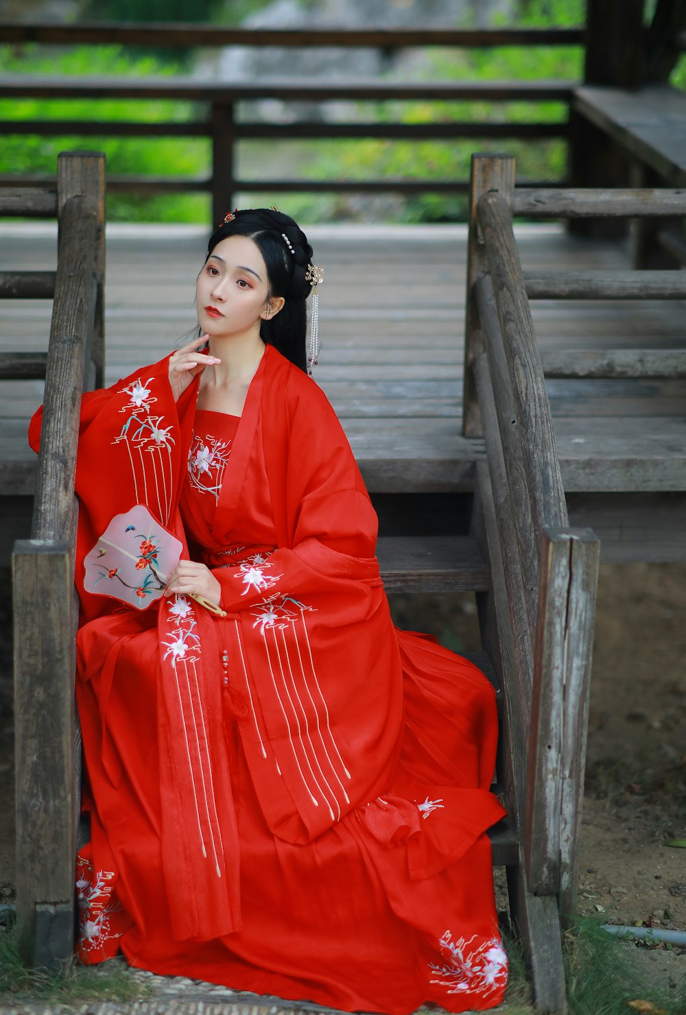 woman in red long sleeve dress sitting on brown wooden bench