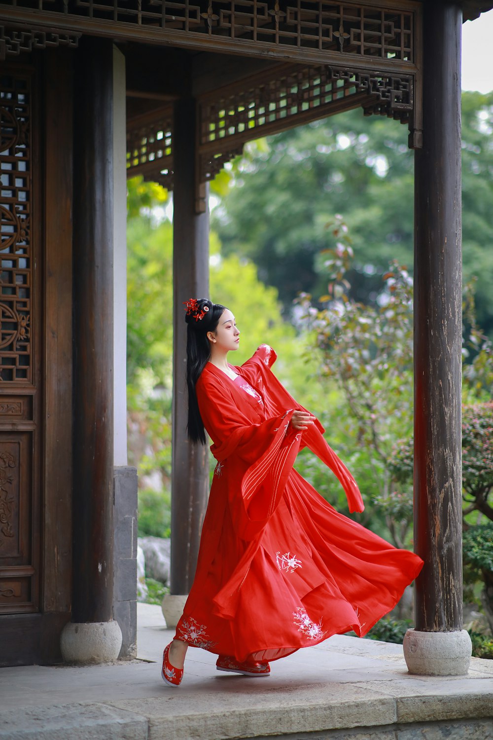 갈색 나무 문 근처에 서 있는 검은 선글라스를 쓴 빨간 드레스를 입은 여자