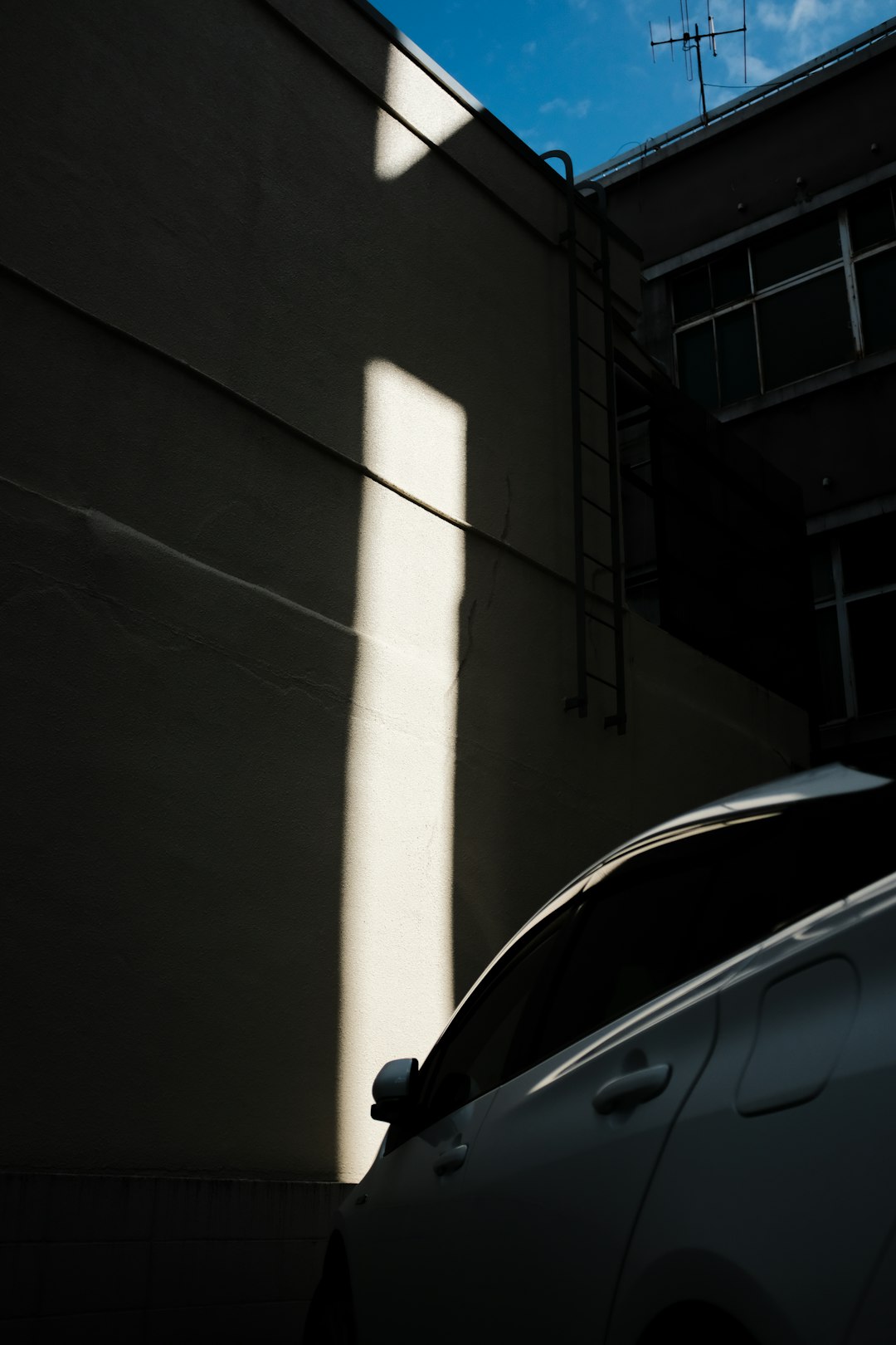 black car parked beside white concrete building