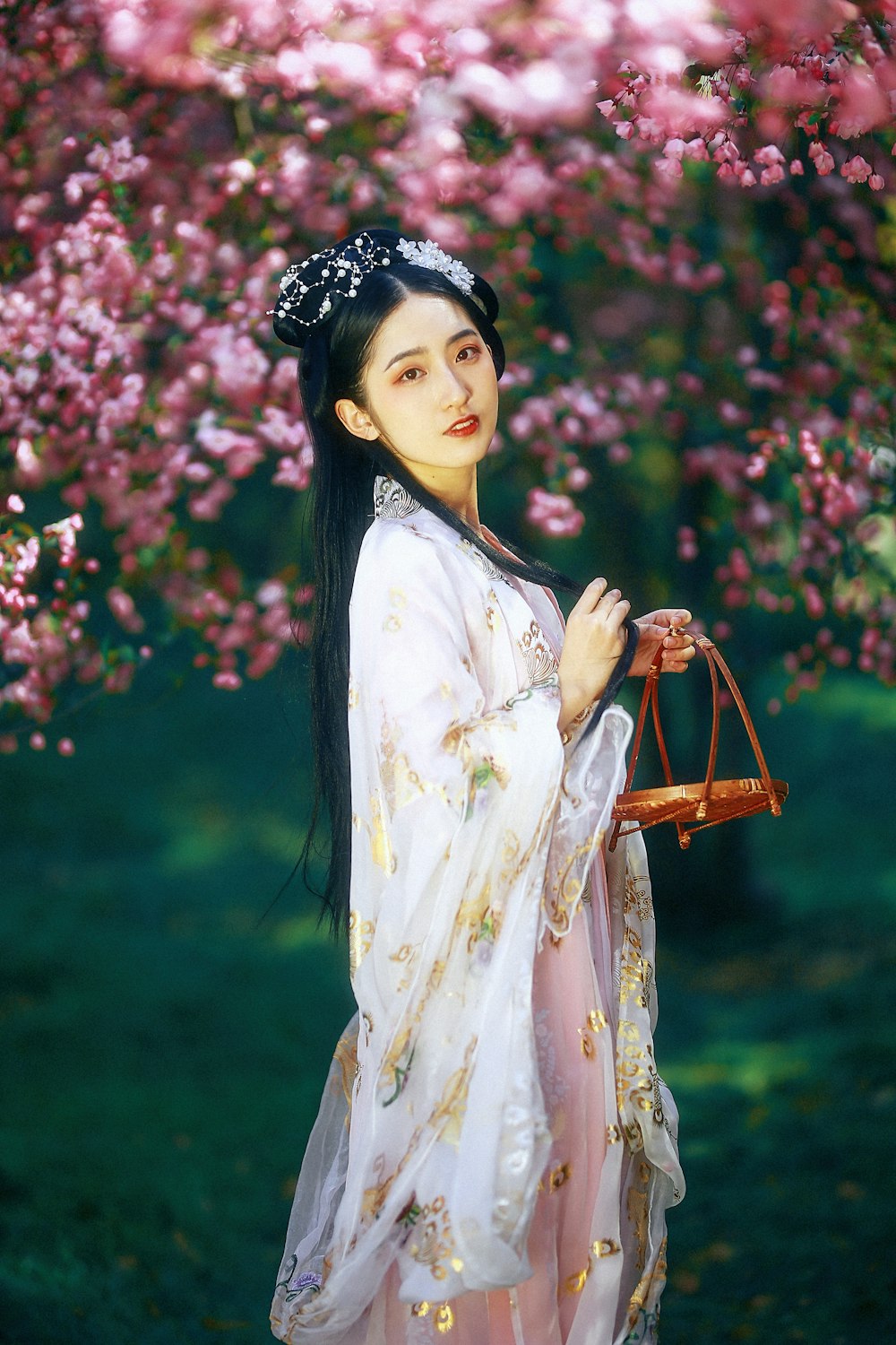 woman in white and yellow floral dress standing near pink flowers during daytime