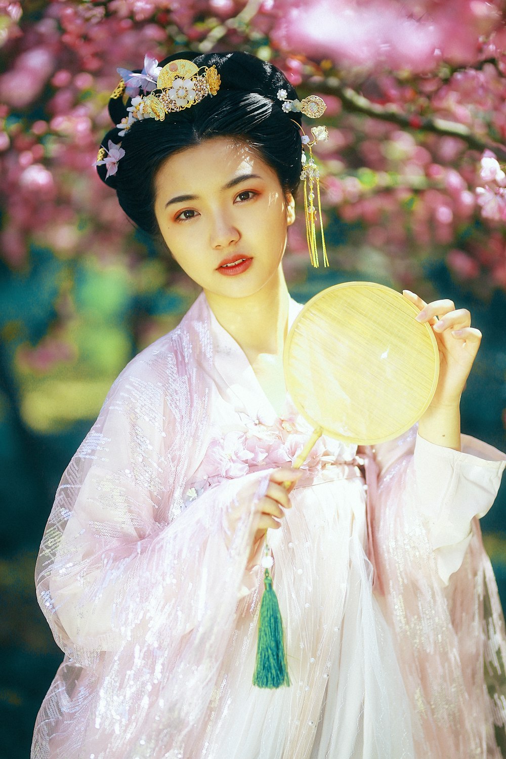 woman in white and pink floral dress holding brown wooden hand fan