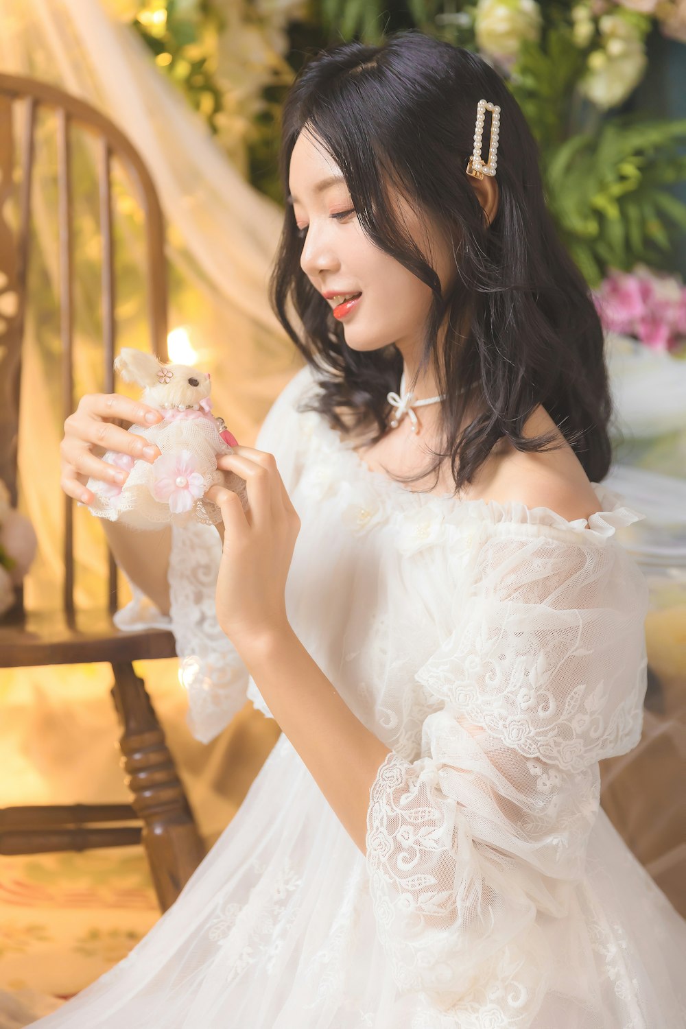 woman in white floral dress holding white string lights