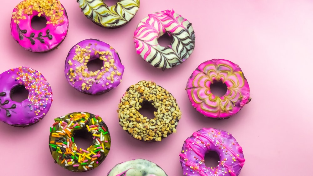 a bunch of doughnuts that are on a pink surface