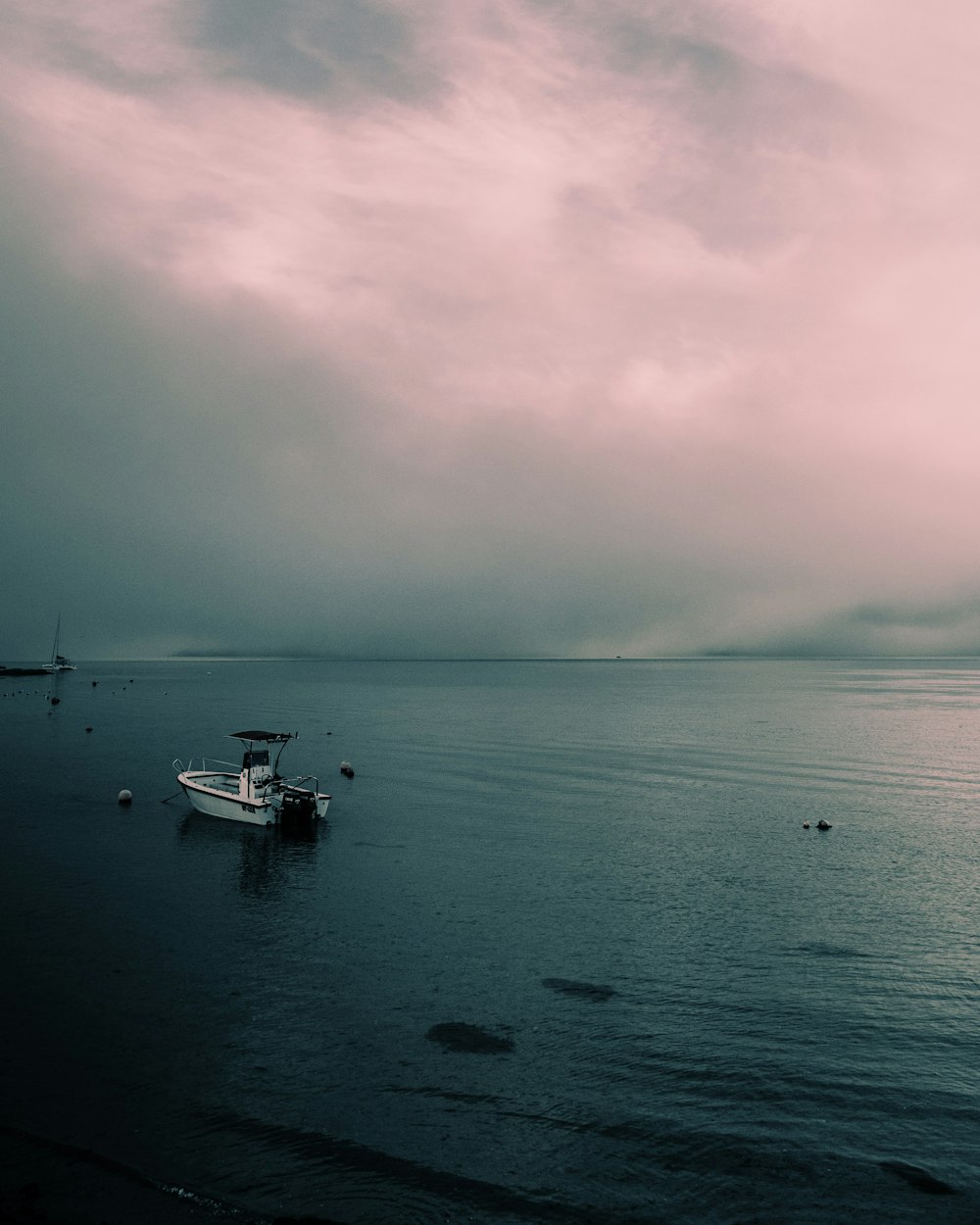 white boat on sea under cloudy sky