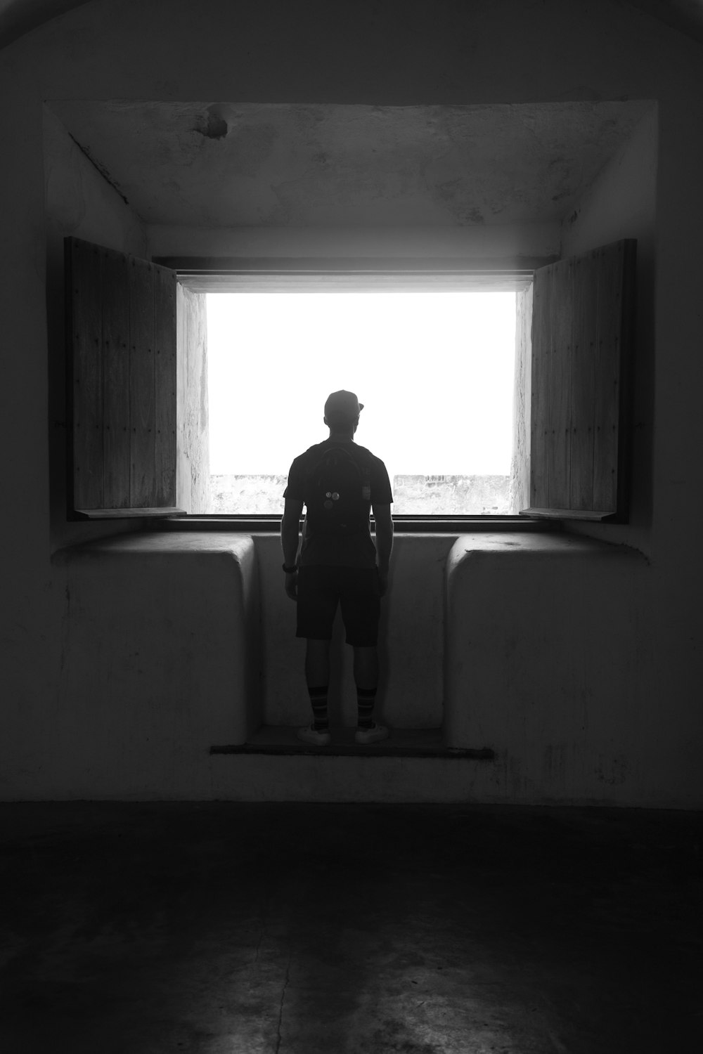 man in black shirt standing in front of window