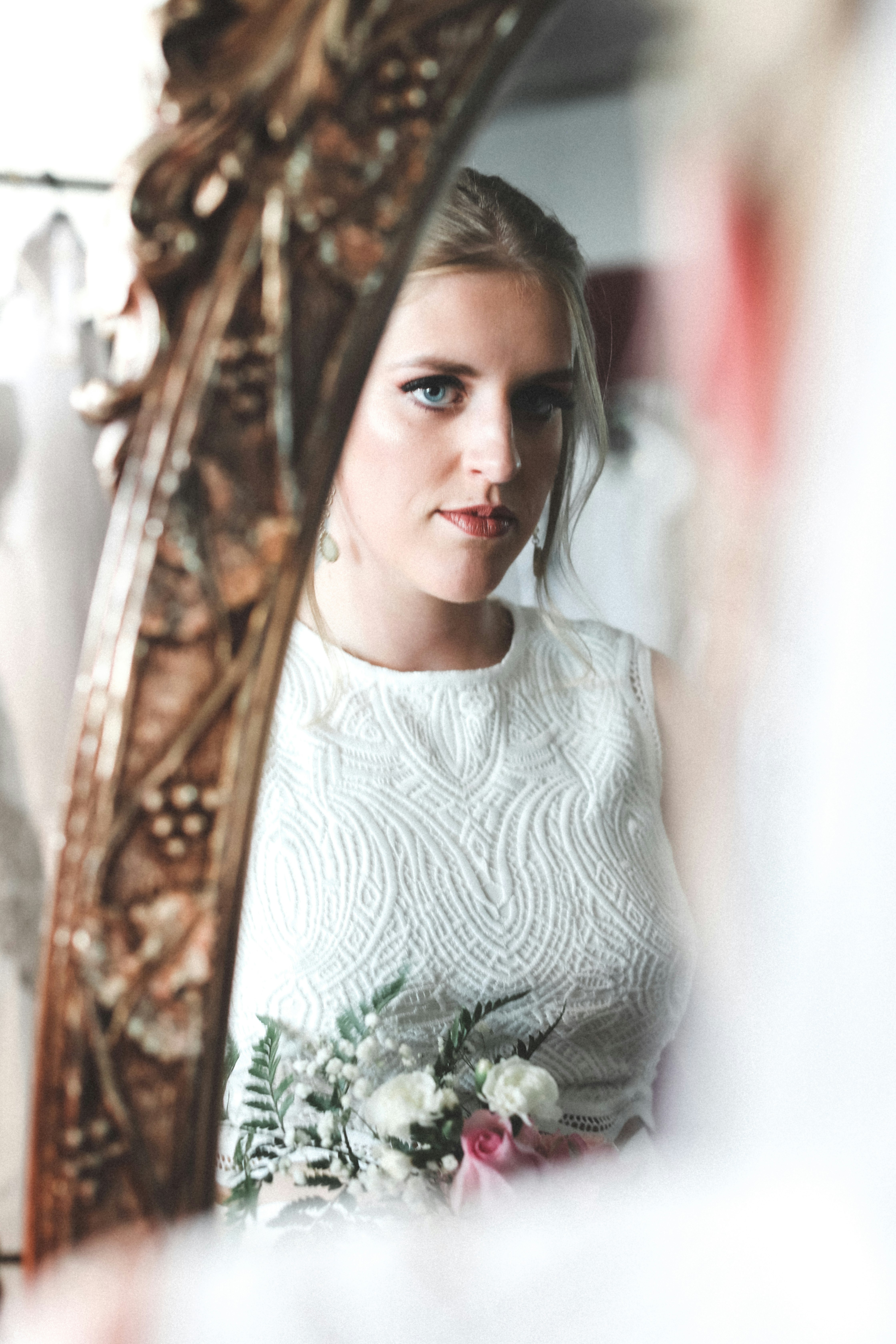 Young woman pensively staring at herself in the mirror before the ceremony. 