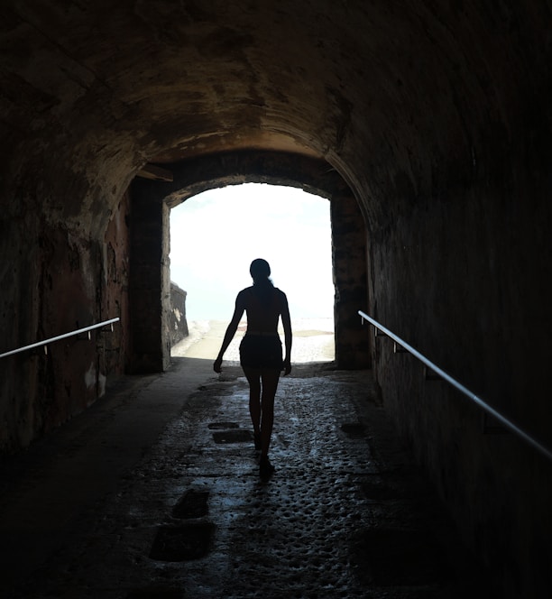 silhouette of person walking on tunnel