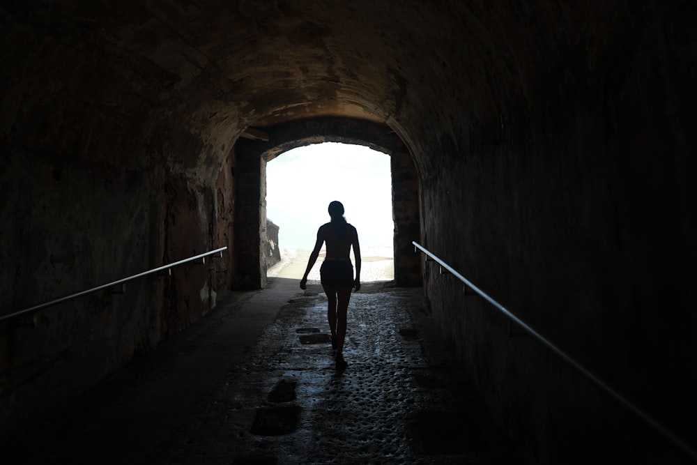 silhouette of person walking on tunnel