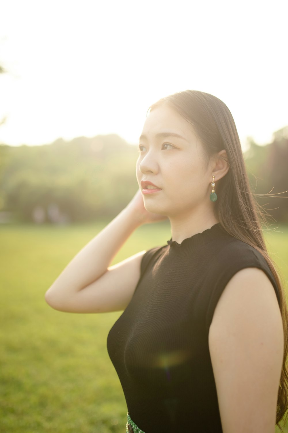 woman in black tank top standing on green grass field during daytime