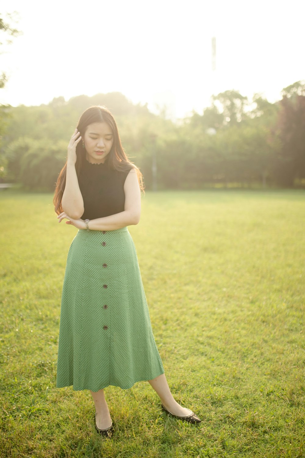 woman in green spaghetti strap dress standing on green grass field during daytime