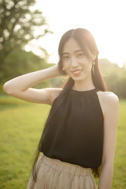 A smiling young woman wearing a soft, breathable t-shirt designed for sensory comfort, standing in a sunlit park.