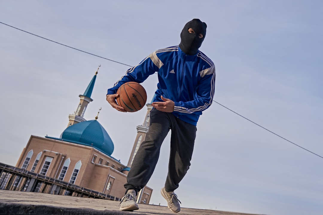 man in blue jacket and gray pants holding basketball