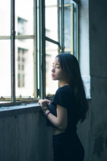 A serene setting featuring a woman applying hair oil by a window.
