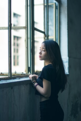 A serene setting featuring a woman applying hair oil by a window.