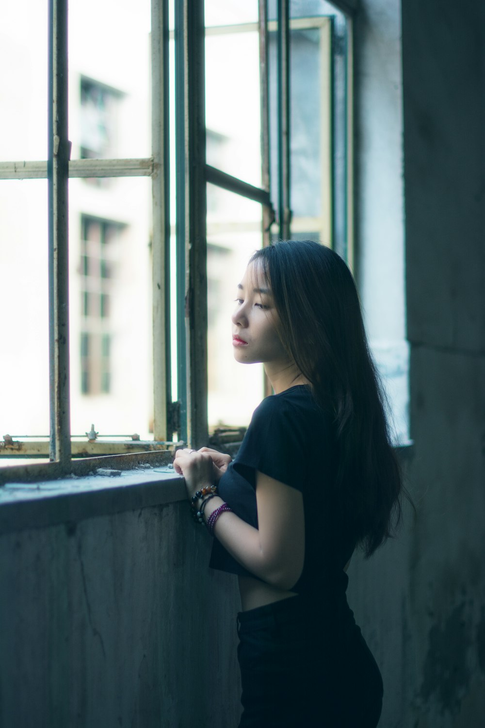 woman in black t-shirt leaning on window