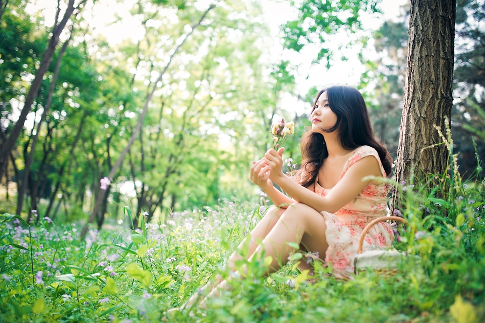 woman in white dress sitting on green grass during daytime