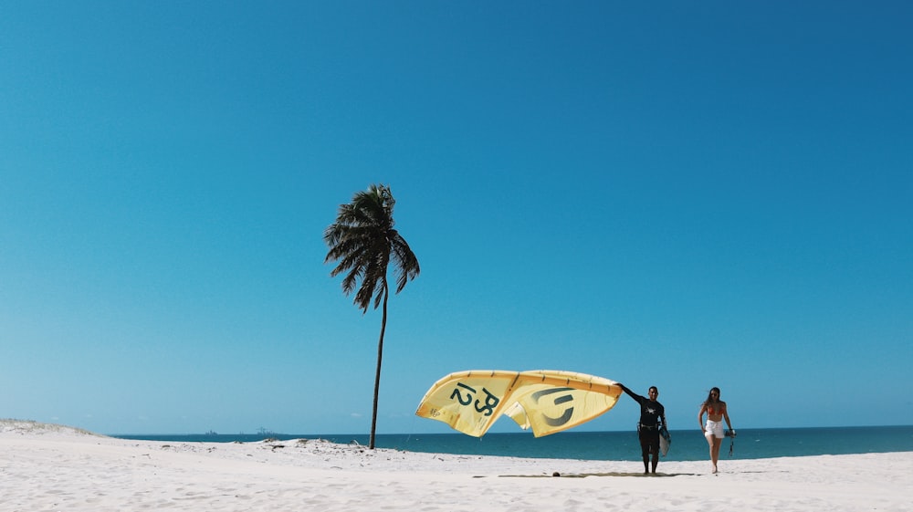man in black shirt holding yellow surfboard walking on beach during daytime