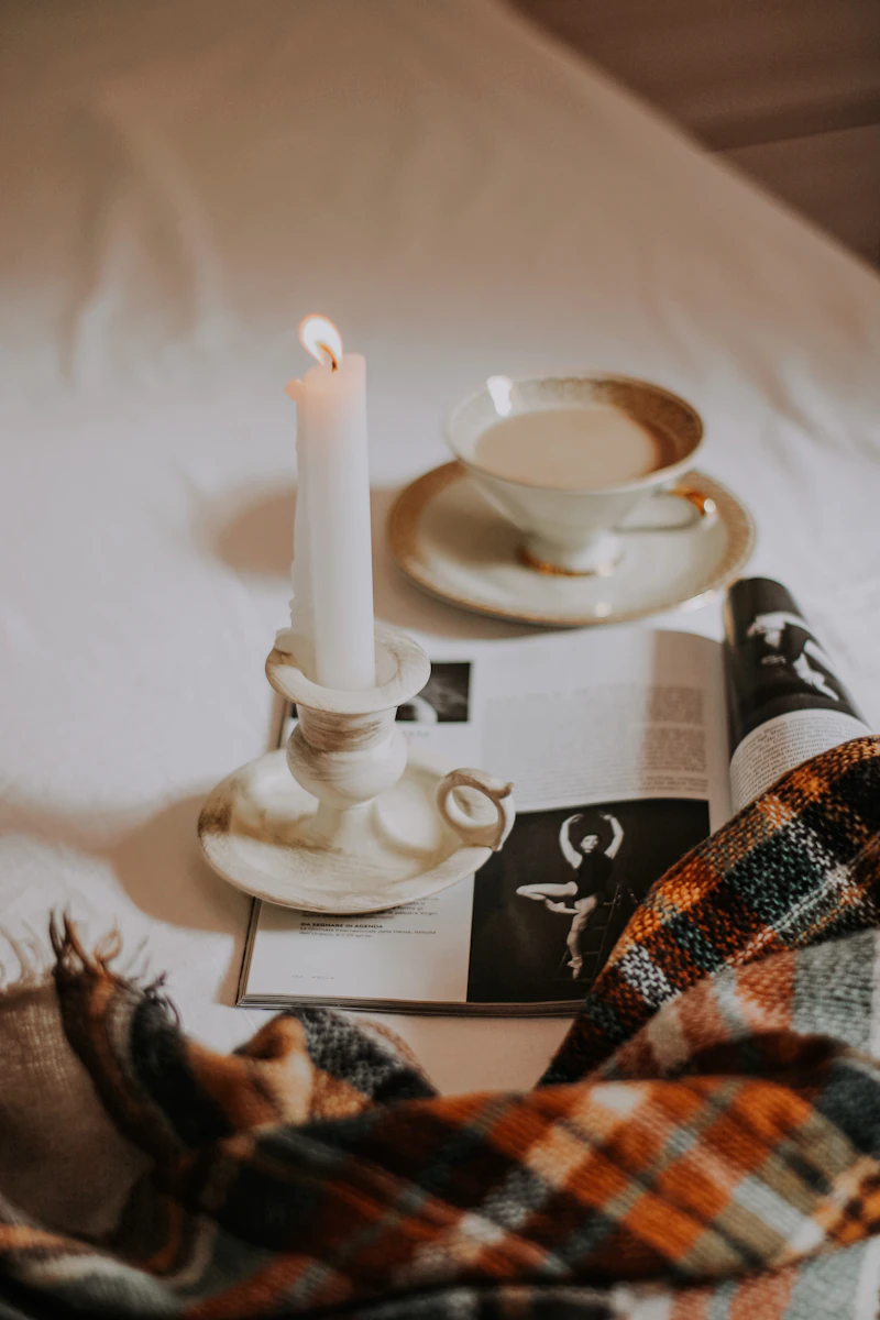 White cup and saucer beside a white candle holder