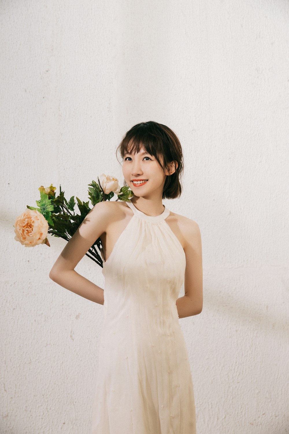 woman in white sleeveless dress holding bouquet of flowers