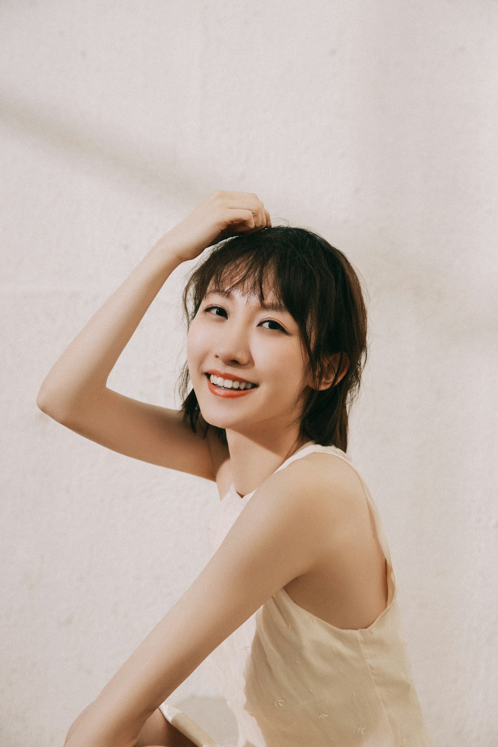 topless woman smiling and standing near white wall