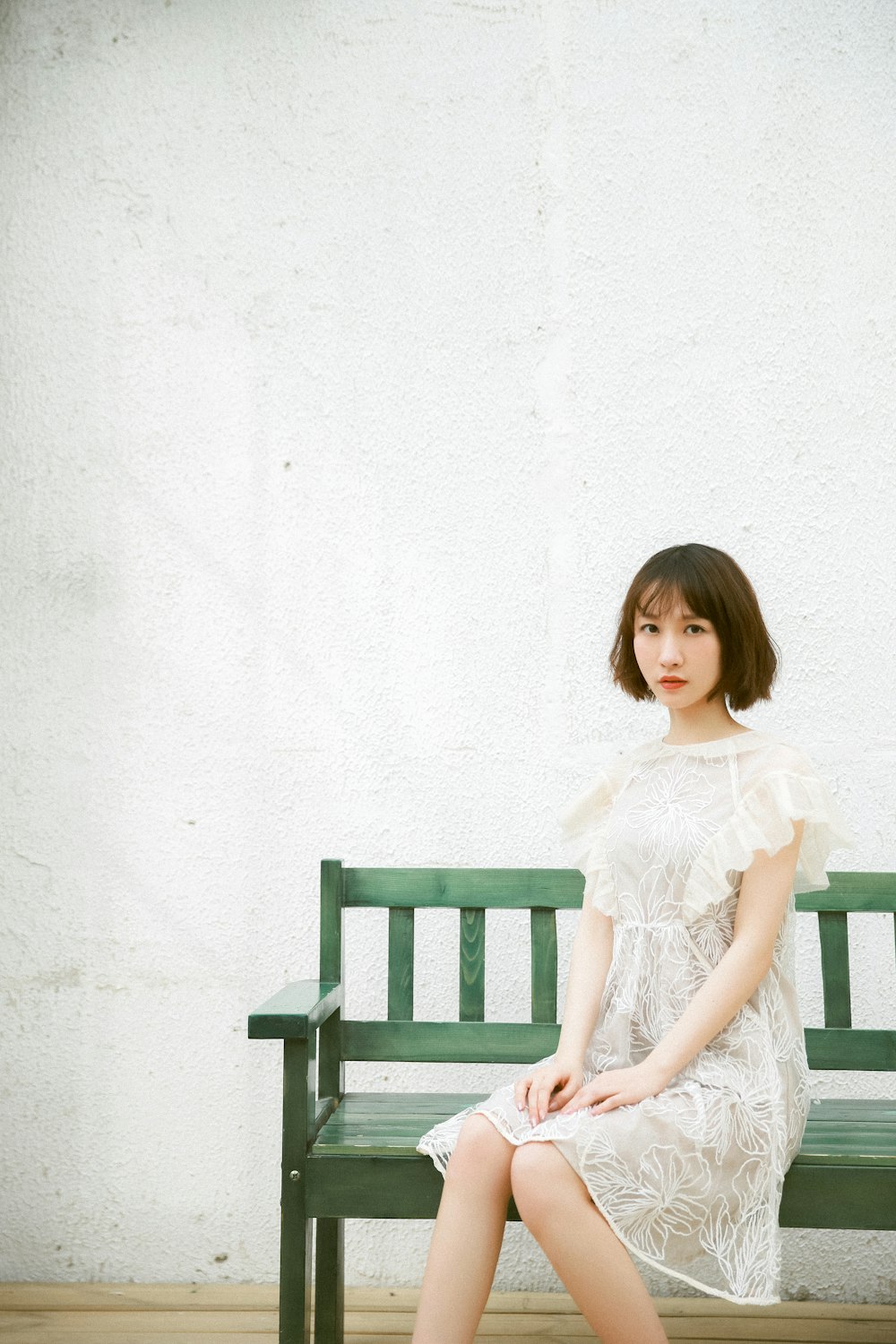 girl in white dress sitting on brown wooden bench