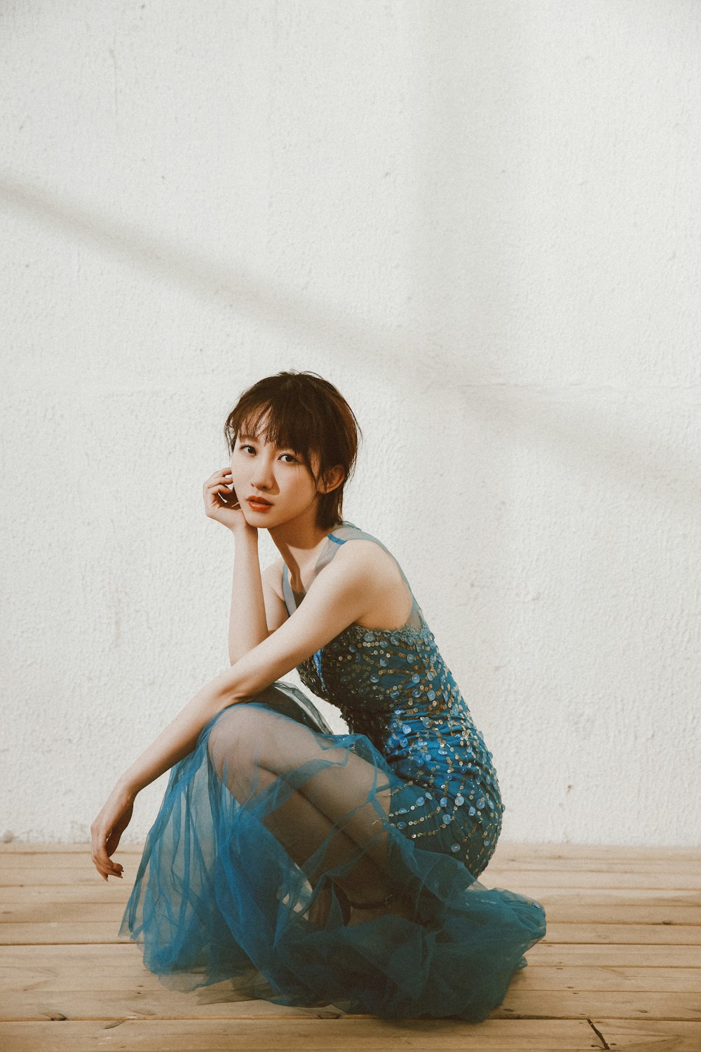 woman in blue and white spaghetti strap dress sitting on brown wooden bench