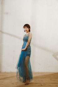 A sophisticated model in a sleek evening gown smiling confidently indoors.