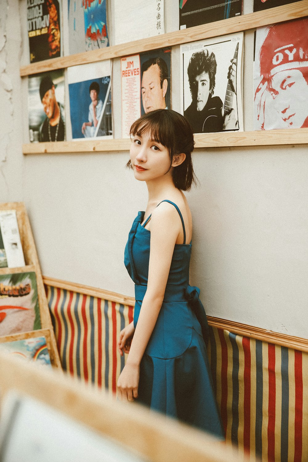 woman in blue sleeveless dress standing near wall