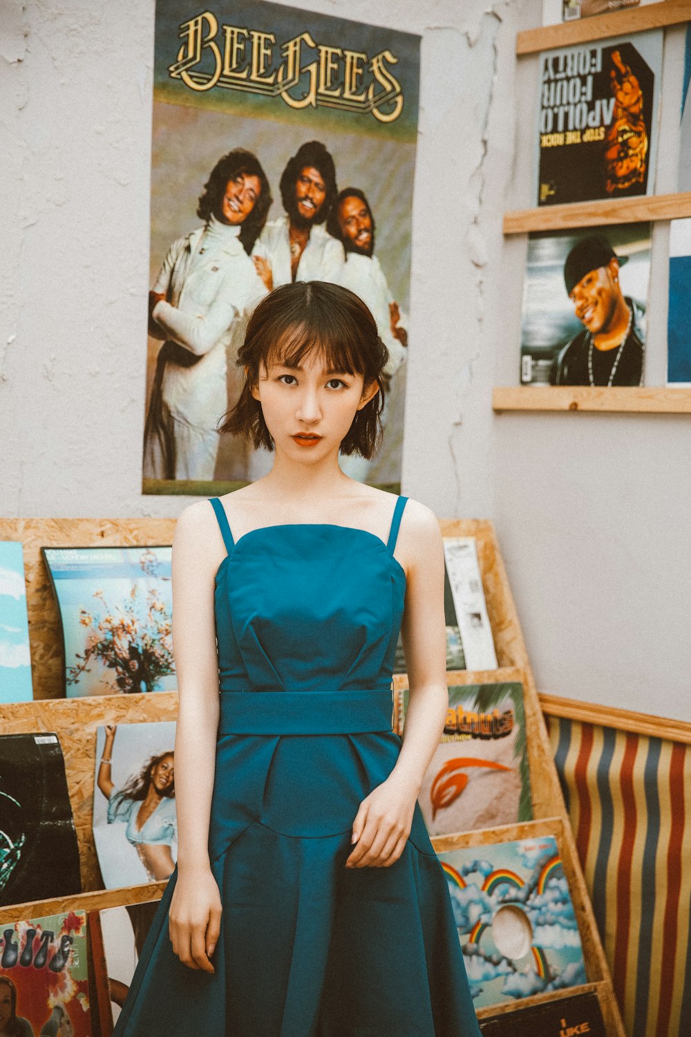 写真の横に立つ青いノースリーブのドレスを着た女性