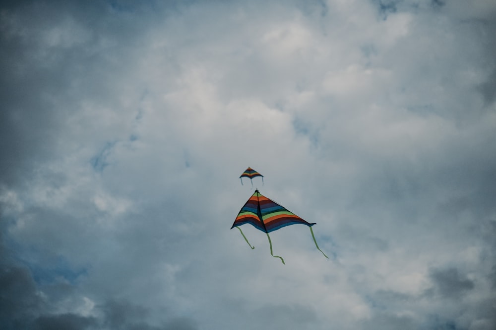 red yellow and blue kite flying under white clouds during daytime