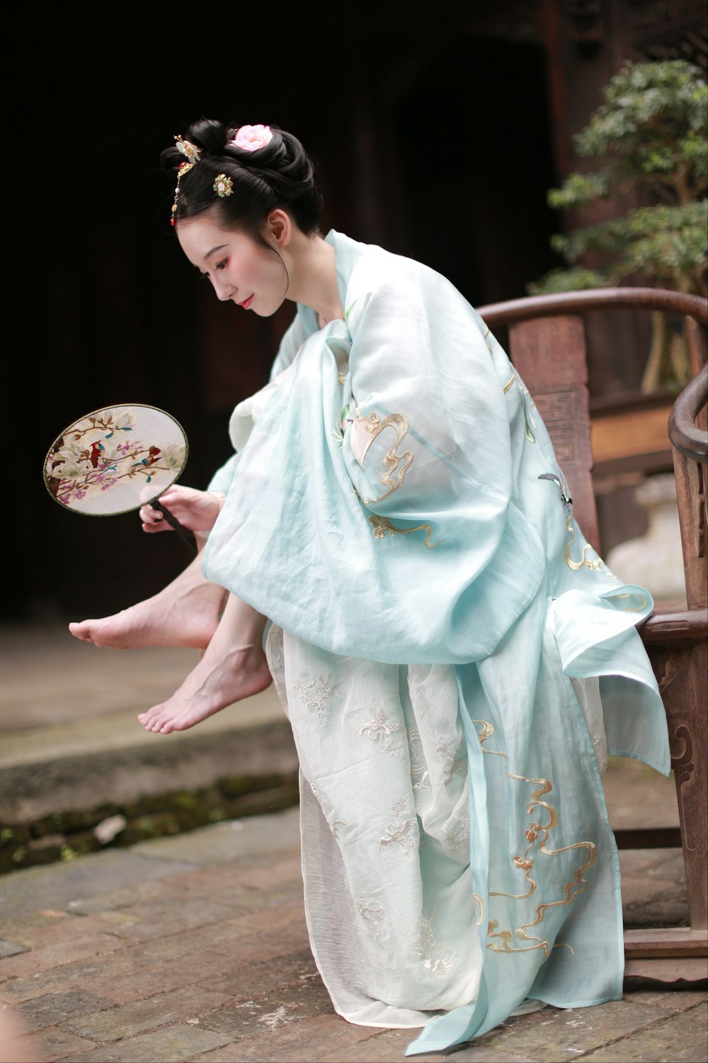 Frau in weiß und blau geblümtem Kimono mit weißem und rosa geblümtem Handfächer