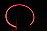 Cinematic close-up of a black oversized hoodie with glowing red angelic embroidery on a dark gradient background.