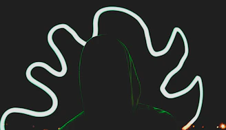 Close-up of a black hoodie featuring a mysterious monochrome silhouette print under soft neon lighting