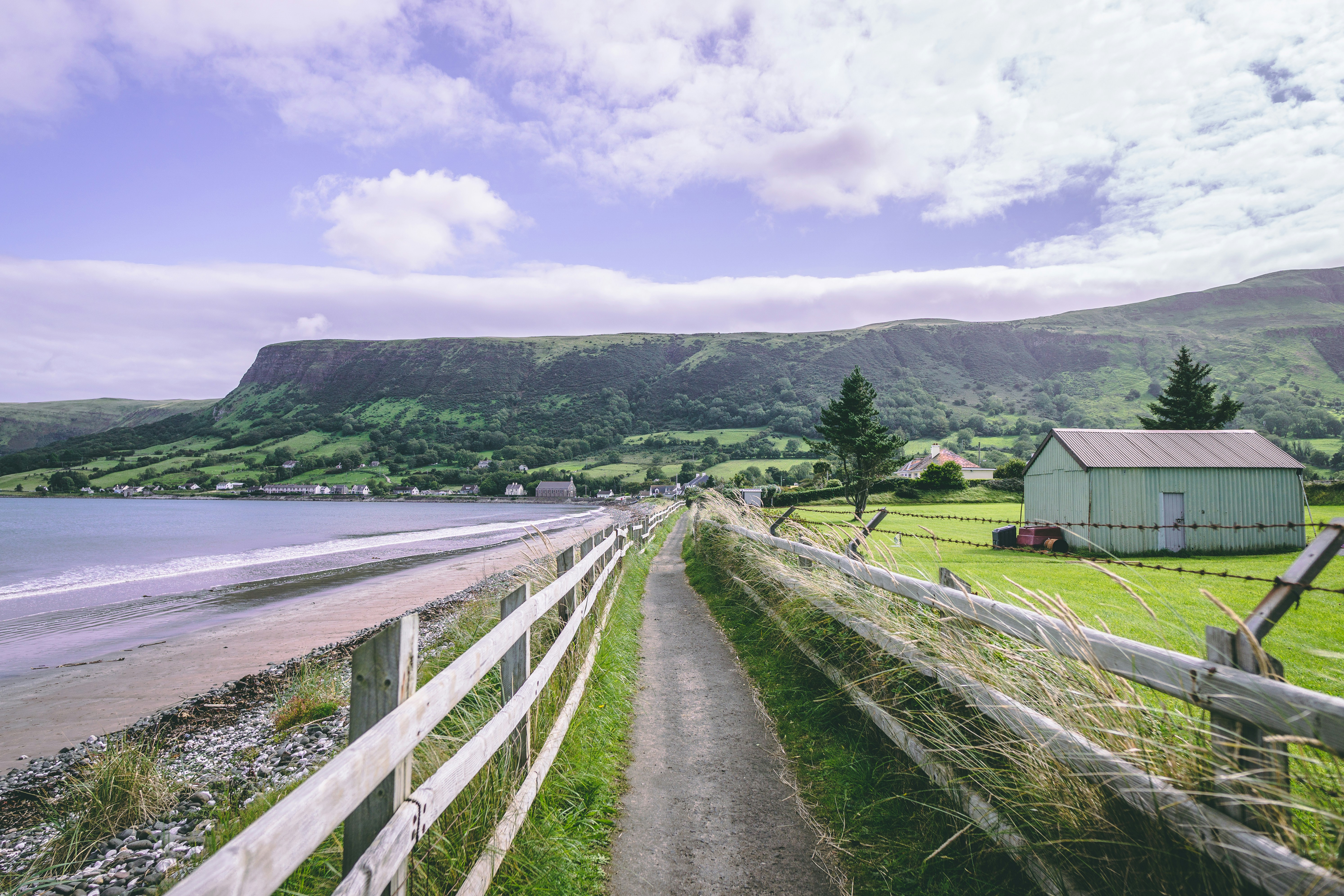 Brown wooden house near green grass field and body of water under white ...
