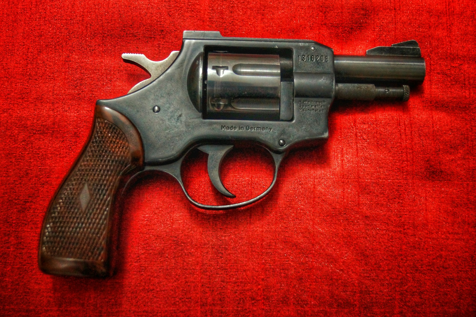 a vintage revolver with a red backdrop